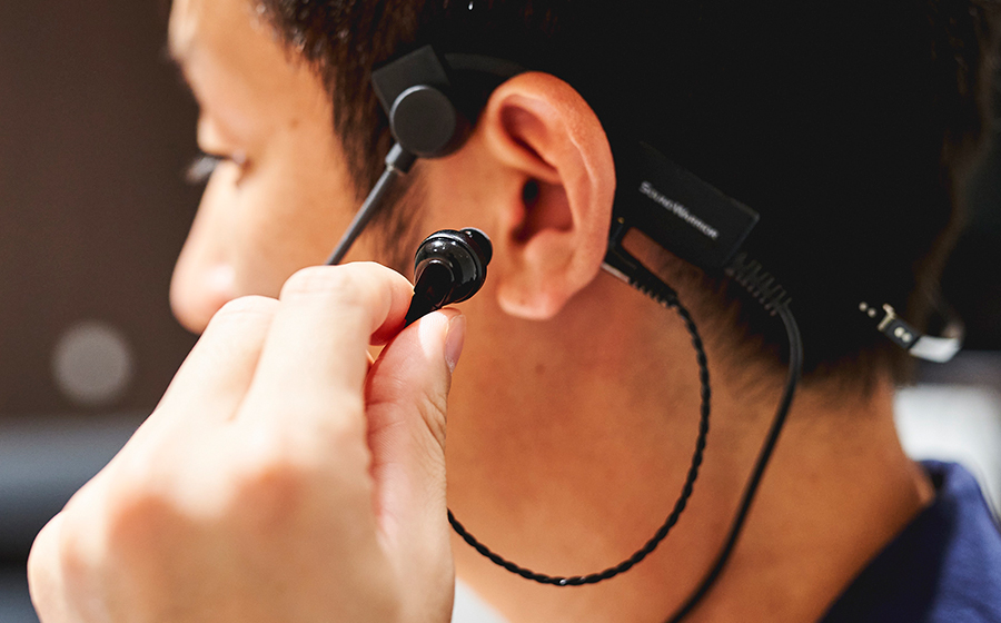 城下工業SOUND WARRIOR折りたたみ式ヘッドセットSW-HW1を男性が片耳イヤホンを耳に装着している