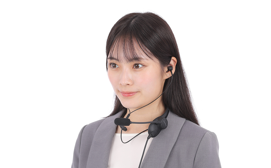 女性が日本製の城下工業 SOUND WARRIORのSW-NS1を首にかけ、両耳イヤホンをつけて前を見ている