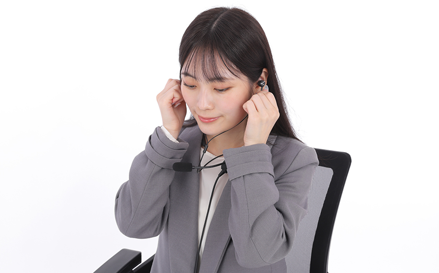 女性が日本製の城下工業 ヘッドセットSOUND WARRIORのSW-NS1を首にかけ、両耳イヤホンをつけている装着の様子