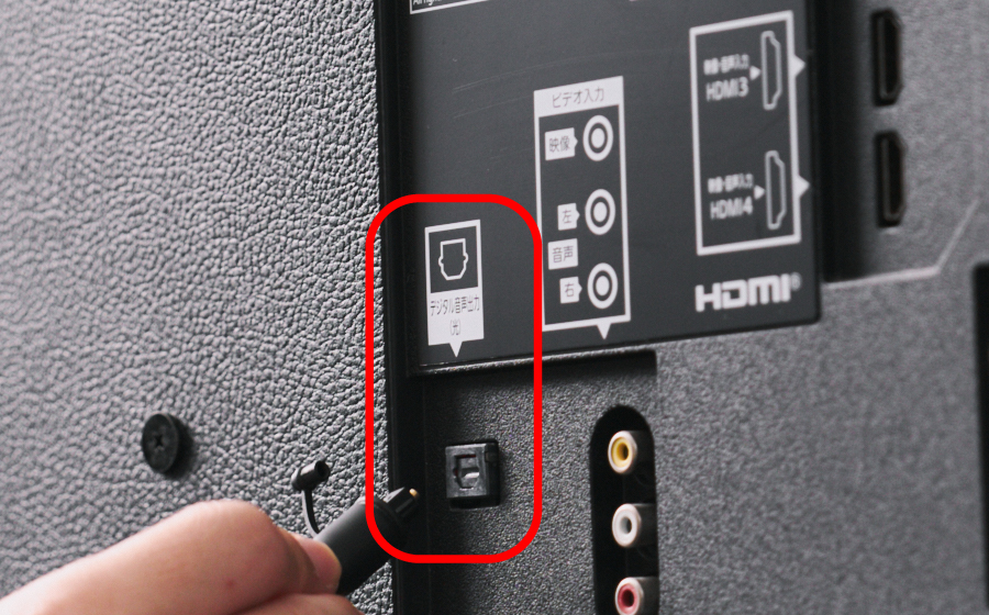 テレビの光デジタル出力端子に、光デジタルケーブルを挿そうとしている写真